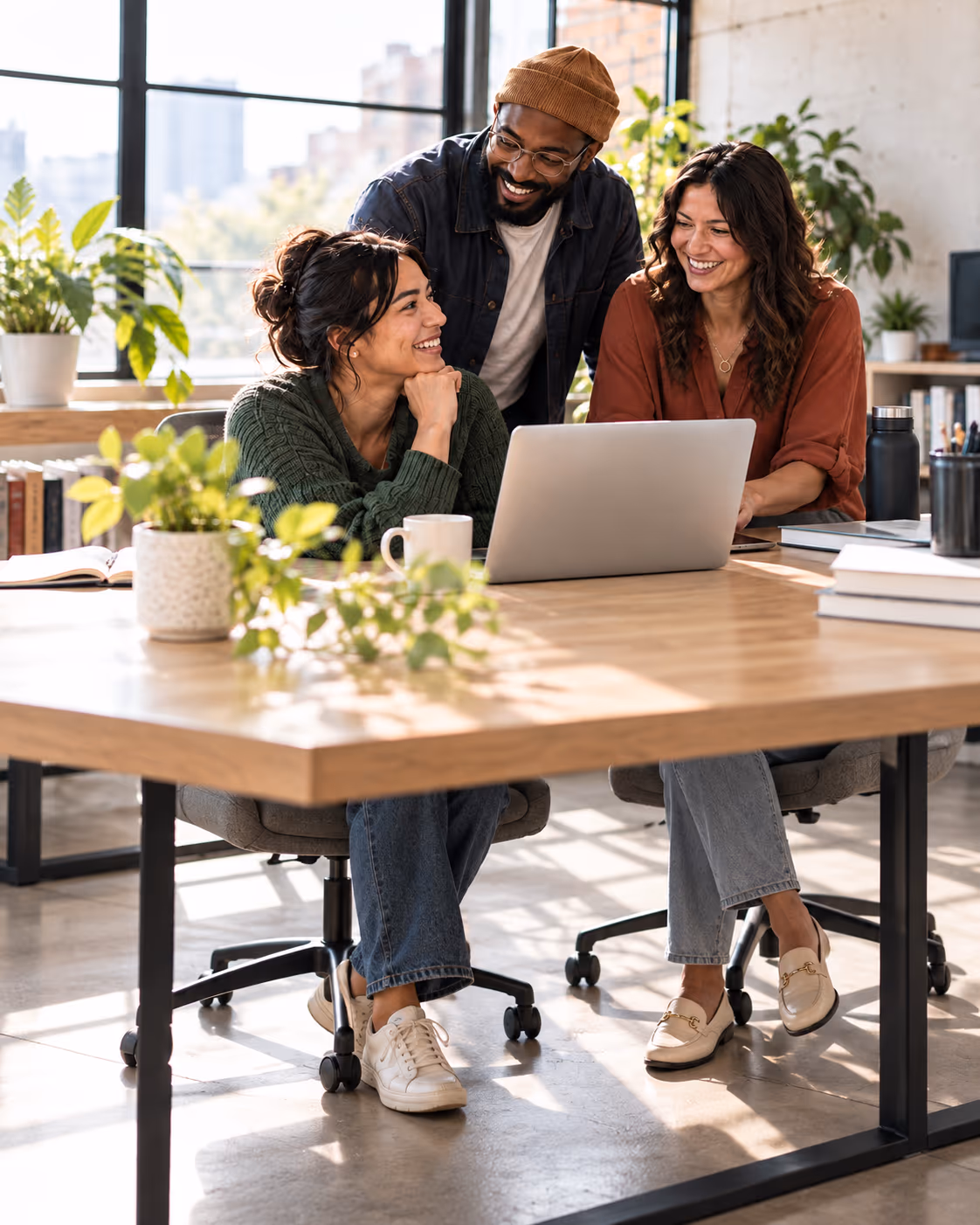 A customer engagement team collaborating around a laptop at a shared desk